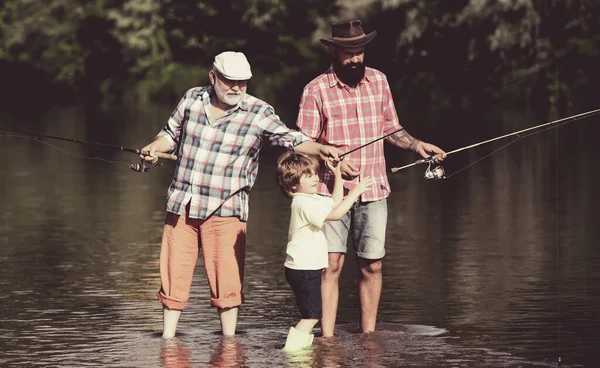 Generazione familiare e concetto di persone. Padre che insegna al figlio a pescare a mosca nel fiume. L'uomo in epoche diverse . — Foto Stock