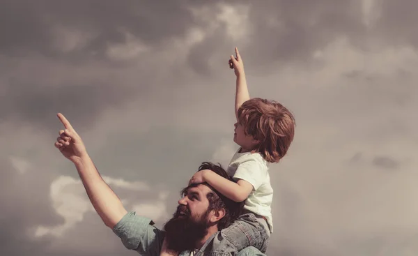 Festa dei padri. Bel ragazzo con papa 'che gioca all'aperto. Bambino felice che punta sullo sfondo del cielo estivo. — Foto Stock