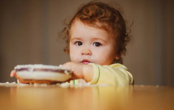 Bebê bonito com uma colher e um prato na cozinha em casa. — Fotografia de Stock