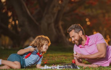 Baba ve oğul parkta birlikte satranç oynuyorlar. Akıllı çocuk, akıllı çocuklar..