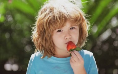Yeşil yaz geçmişinde taze çilekleri olan mutlu çocuk..
