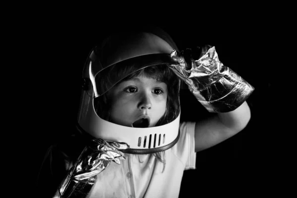 Un niño sueña con convertirse en astronauta y volar al espacio. Cosmos niños en traje espacial y sueños casco. De cerca la cara de los niños emocionados en color neón. — Foto de Stock