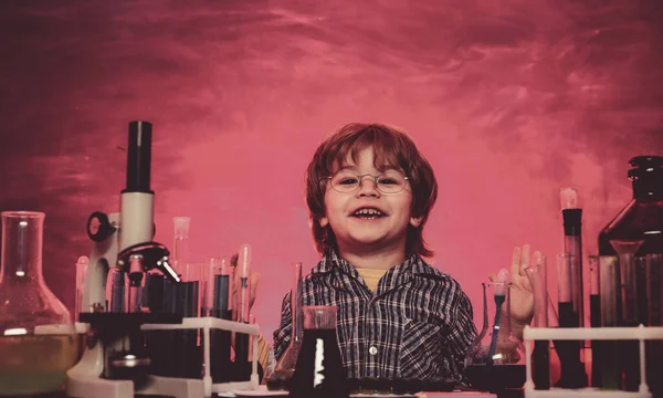 Glada leende liten pojke som har kul mot blå vägg. Skolkemilektioner. Förskollärare. Det som lärs ut i kemi — Stockfoto