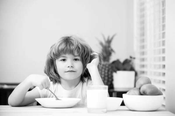 चमच्याने घरी टेबलावर जेवण घेतलेल्या सुंदर मुलाचे सूप जेवण किंवा नाश्ता खाण्याचे पोर्ट्रेट लहान मुले निरोगी अन्न . — स्टॉक फोटो, इमेज