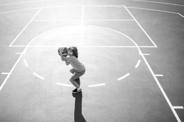 Vinkel vy från ovanpå liten pojke unge spelar basket på lekplatsen. — Stockfoto