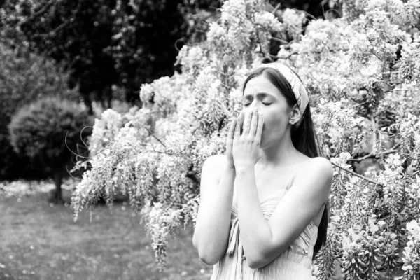 Lány tüsszentés allergia tünet koncepció. Az a nő, aki allergiás a virágzásra a kint virágzó fa tavaszi előterében. — Stock Fotó
