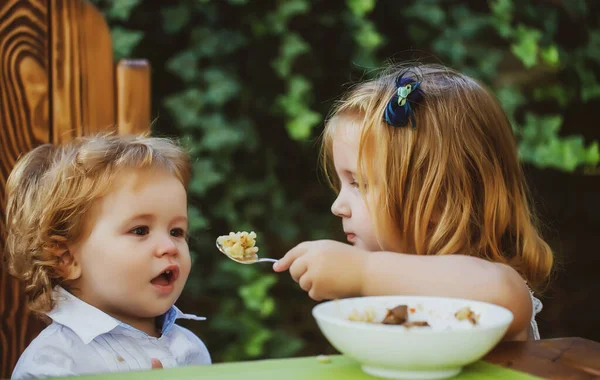 Zuster voedende broer. Meisje voedt kleine jongen met een lepel. Kindervoeding. — Stockfoto