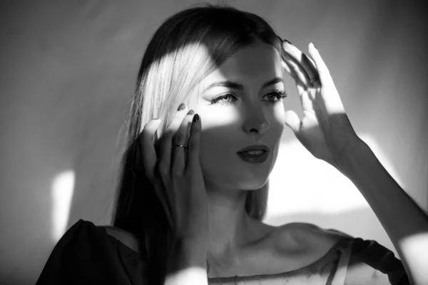 Elegante jovem posando sobre fundo preto. Luz e sombra. Retrato de um rosto de mulher de beleza. — Fotografia de Stock