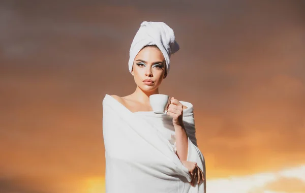 Расслабленная женщина в халате нюхает кофе ночью на ярком небосводе. Роскошная красивая голая девушка. — стоковое фото