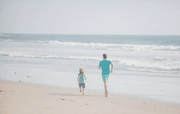 父と息子は海を走っている。父と子供は屋外で楽しんでいます。家族旅行、休暇、父の日の概念. — ストック写真