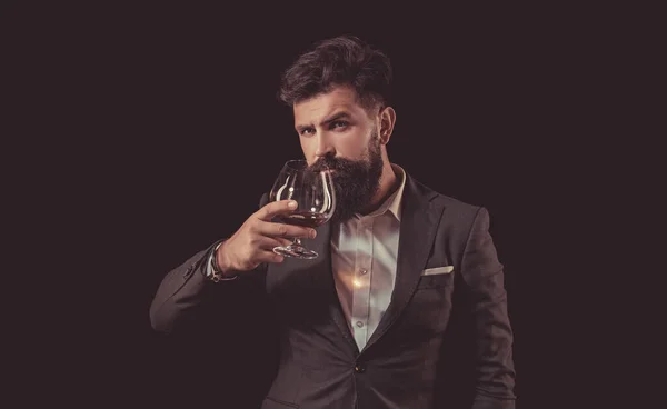Koncepcja alkoholu. Luksusowa koncepcja napojów. Barman z brodą trzyma szklaną brandy. Koncepcja stylu mody. Człowiek pijący alkohol ze szkła. — Zdjęcie stockowe