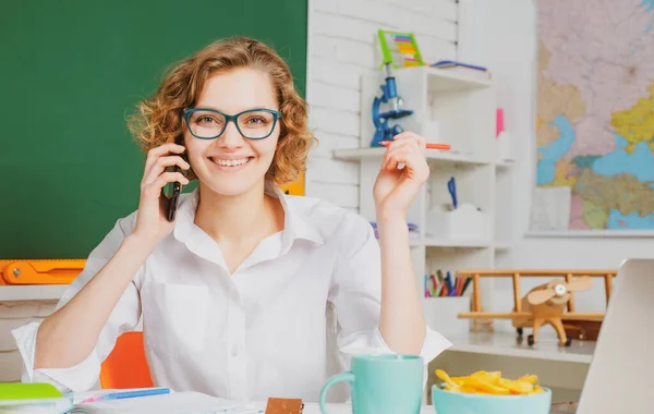 Lehrerin mit Handy im Klassenzimmer auf der Tafel. Hochschule mädchen im klasse. — Stockfoto