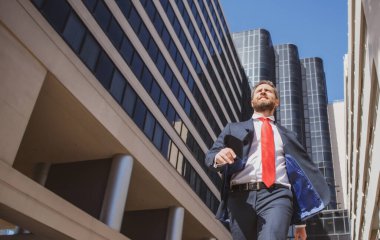 Sokakta yürüyen bir iş adamı. İş adamı modern iş merkezinin yanında yürüyor. İş ve mimari kavramı.