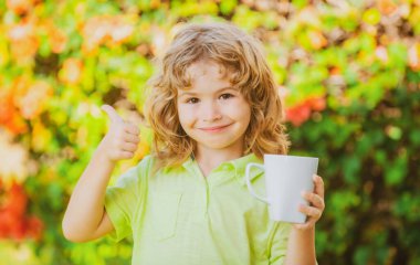 Genç çocuk güneşli bir yaz gününde bardaktan meyve suyu içiyor..