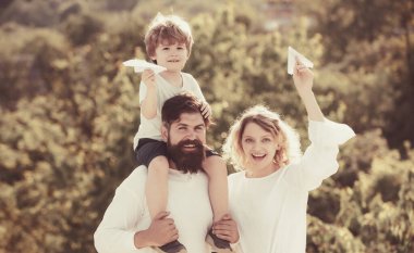 Ebeveynlik ve çocukluk kavramı. Baba, anne ve oğlu dışarıda oynuyorlar. Baba ve oğul eğleniyor ve doğada oynuyorlar. Baba oğlunu omuzlarında taşıyor..