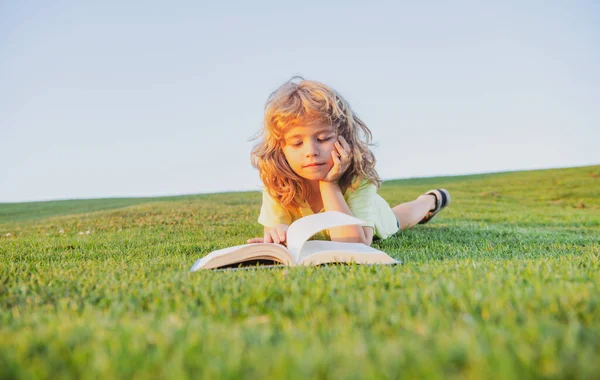 Niño inteligente leyendo libro en el parque al aire libre en el día de verano. Niños listos.. — Foto de Stock