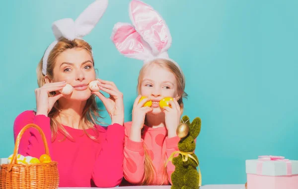 Matka i córka w uszach króliczka na Wielkanoc gospodarstwa jaj, izolowane na niebiesko. — Zdjęcie stockowe