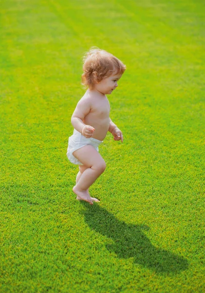 Varm vår i parken. Baby i vackra våren grönt fält. Första steget. — Stockfoto