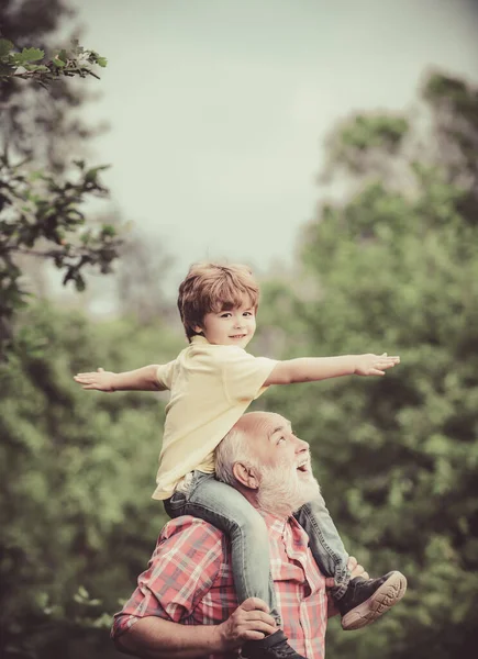 Großvater im Gespräch mit Enkel. Kleiner Junge und Großvater heben die Hände über dem Sonnenuntergang und genießen das Leben und die Natur. Papa und Junge lächeln und umarmen. — Stockfoto