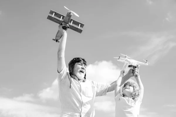 Velho avô e neto criança com avião de jetpack de brinquedo e drone quadcopter contra o céu. Aviador piloto criança com sonhos de avião de viajar. — Fotografia de Stock