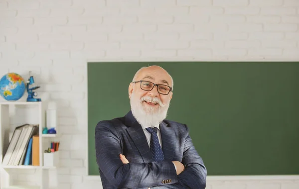 Profesor senior gracioso. Retrato del maestro mayor feliz con los brazos cruzados de pie contra la pizarra. —  Fotos de Stock