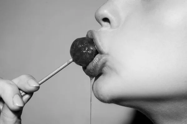 迷人的嘴，用红唇舔着美味的棒棒糖。吸棒棒糖。性感的女性唇。性感女人红唇配棒棒糖糖果吧的概念. — 图库照片