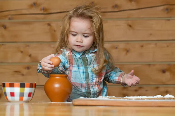 Baby boy in the kitchen cooking, playing with eggs. Baby food, family breakfasts, child plays with kitchen utensils. Child baby boy to break the egg. — Stock Photo, Image