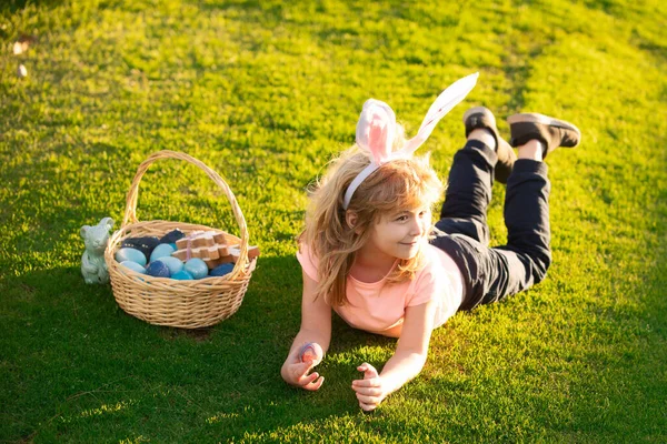 Kinderen vieren Pasen. Kind in konijnenkostuum met konijnenoren buiten. Pasen kinderen met konijnenoren en op gras achtergrond. — Stockfoto