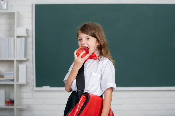 Éducation et connaissance des enfants. Des élèves. Portrait de belle fille avec pomme rouge dans la salle de classe. — Photo