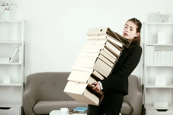 Femme d'affaires bouleversée tenant de nombreux dossiers avec les documents, fille secrétaire malheureuse travaillant des heures supplémentaires au bureau. Solution du problème. — Photo