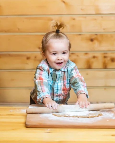 Divertente immagine di baby chef giocare con farina su sfondo cucina in legno. Ritratto di bambino che fa la panetteria fatta in casa in cucina. Bambino seduto sul tavolo e godere imparare a cucinare cibi o cottura. — Foto Stock