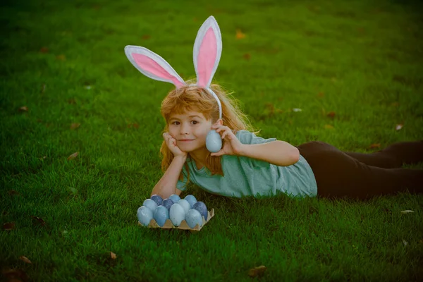Παιδί με αυτιά λαγού που κυνηγά πασχαλινά αυγά. Το παιδί διασκεδάζει στο πάρκο. Πασχαλινό κυνήγι αυγών. Ανοιξιάτικες διακοπές. — Φωτογραφία Αρχείου