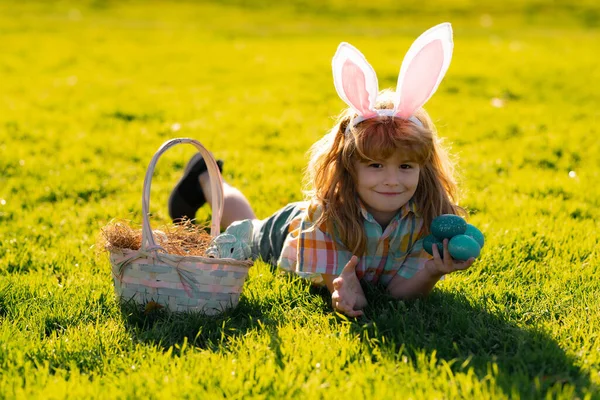 Niños conejitos de Pascua. Niño en orejas de conejo cazando huevos de Pascua en el parque al aire libre. Vacaciones de primavera. — Foto de Stock