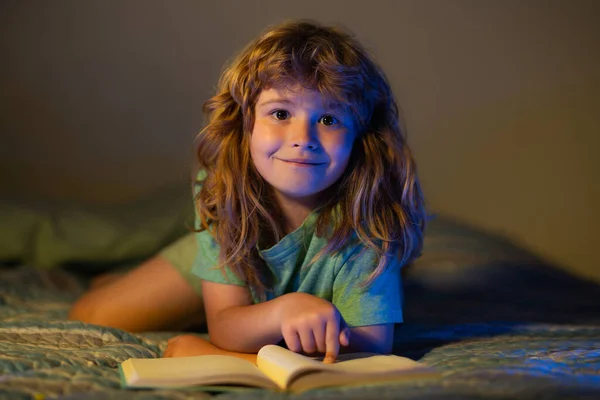 Dzieci czytają bajki. Dziecko czyta książkę w łóżku przed snem. Dziecko czyta książkę na dobranoc. Chłopiec czyta bajki na dobranoc, bajki. — Zdjęcie stockowe