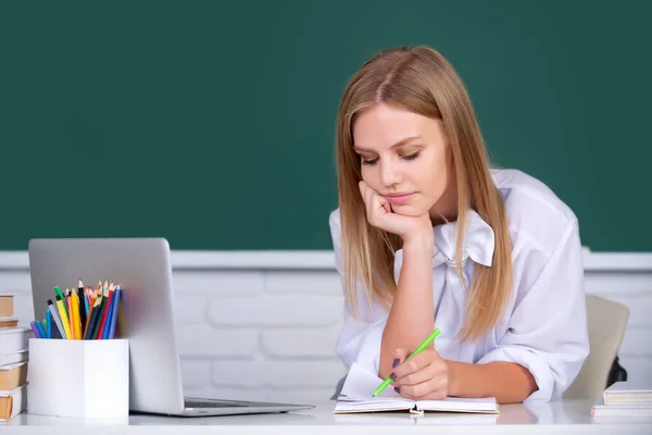 Vrouwelijke studente werkt aan een laptop in de klas, bereidt zich voor op een examen. Studenten onderwijs concept. Vrouwelijke student die nadenkt over cursuswerk aan de universiteit. — Stockfoto