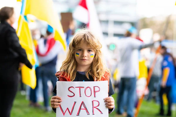 Portret van jongen roept naar Stop oorlog in Oekraïne, met een poster met Stop de oorlog boodschap buiten staan. Russische agressie. Kind draagt een teken Stop oorlog. — Stockfoto