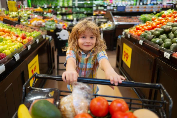 Çocuk süpermarkette alışveriş yapıyor. Çocuk süpermarketten meyve alıyor. Çocuk marketten taze sebze alıyor. Dükkandaki çocuklar, sağlıklı yiyecekler. — Stok fotoğraf