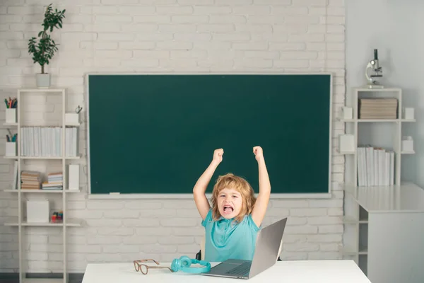 Criança de escola usando laptop pc digital na classe. Miúdo da escola primária zangado e triste. Aluno gritando gritando na sala de aula. Mau menino da escola. — Fotografia de Stock