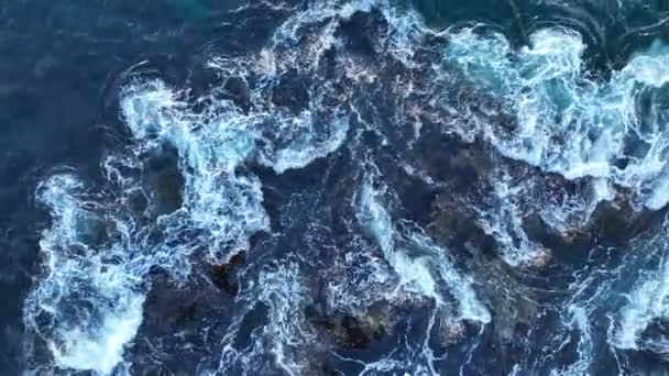 Las olas del océano chocan contra piedras. Las olas del mar se estrellan contra las rocas. Salpicaduras de agua con espuma en las olas. — Vídeo de stock