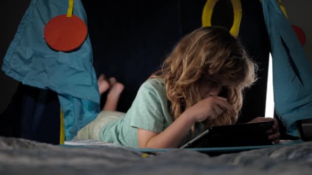 Serious child reading books, looks serious and concentrated, playing at home, reads story or fairytales. Child reading a book in the dark home. — Stock Video