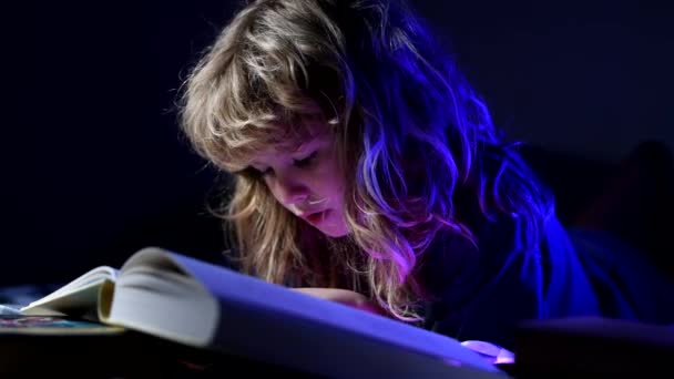 Niño leyendo un libro en la cama antes de irse a dormir. Niño leyendo libro antes de dormir, noche a la hora de acostarse. — Vídeo de stock