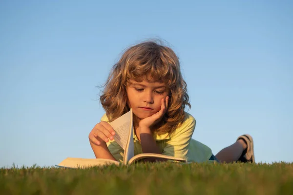 Smart pojke läsa bok i parken utomhus. — Stockfoto