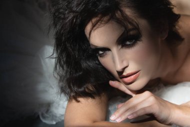 Siyah arka planda poz veren zarif genç bir kadın. Işık ve gölge. Güzel bir kadının portresi. Şehvetli kız yüzü gölgede.