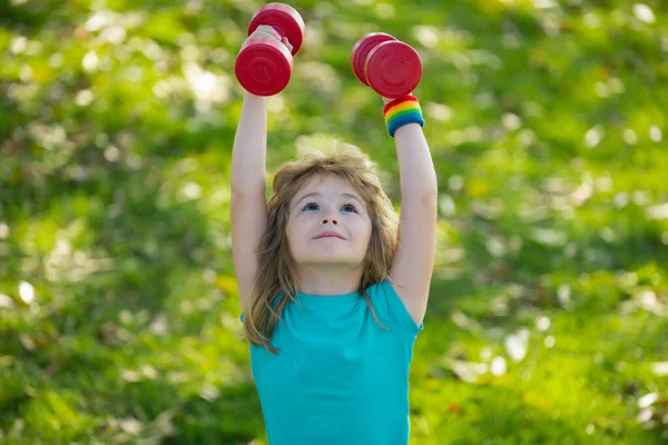 Sport per bambini. Sportivo bambino con manubrio nel parco primaverile. Sport. Fitness per la salute dei bambini energetici. Allenamento di felice piccolo bambino tenere i manubri. Sollevamento pesi per muscoli. Attività infantile. — Foto Stock