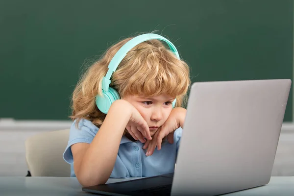 Serieuze kind jongen in hoofdtelefoon studie online, kind in oortjes nemen internet webles. — Stockfoto