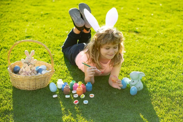 Kinderen vieren dat ze eieren schilderen. Kid in konijn kostuum met konijn oren buiten. — Stockfoto