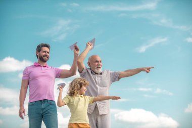 Büyükbaba ve oğul gökyüzünde oyuncak uçakla oynuyorlar. Mutlu bir aile. Üç erkek nesli. Mutlu çocukluk.