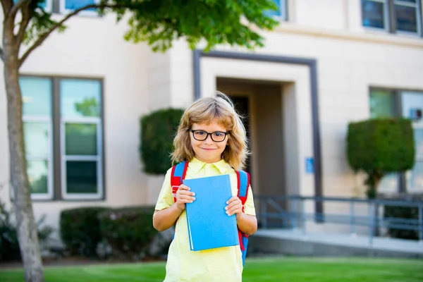 Petit garçon joyeux avec un gros sac à dos s'amusant contre l'école. Concept de retour à l'école. — Photo