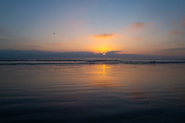 Gökyüzünde gün batımı ve renkli bulutlar. Güneşin doğuşuyla sakin deniz, bahamalar.