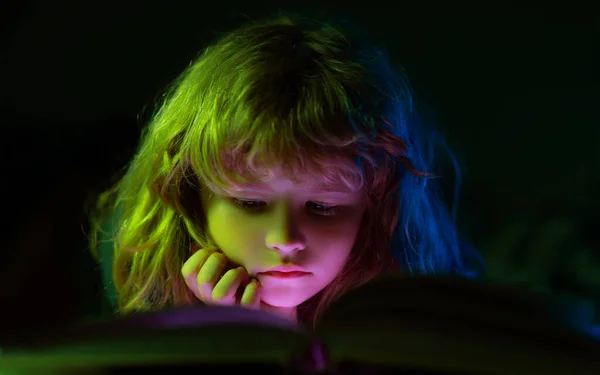 Närbild ansikte barn läser en magisk bok i sängen. Grabben läste böcker hemma.. — Stockfoto
